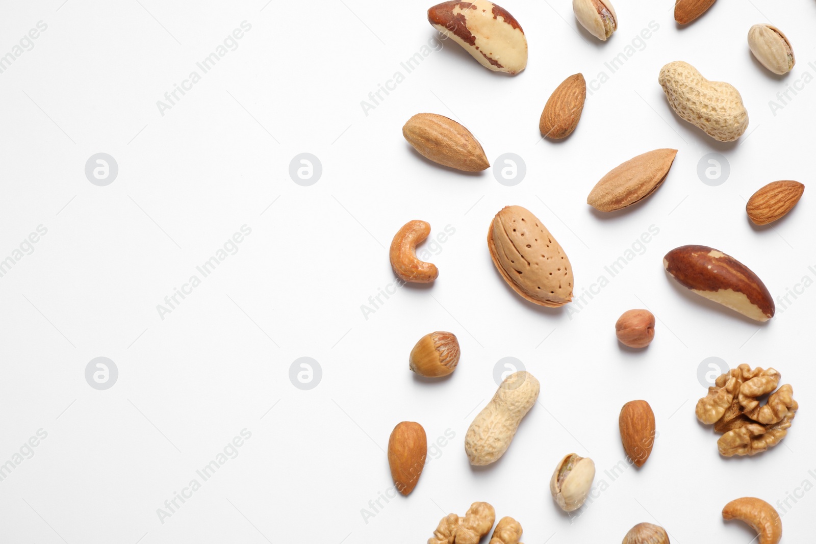 Photo of Different delicious nuts on white background, flat lay. Space for text