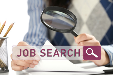 Woman using magnifying glass at table, closeup. Job search