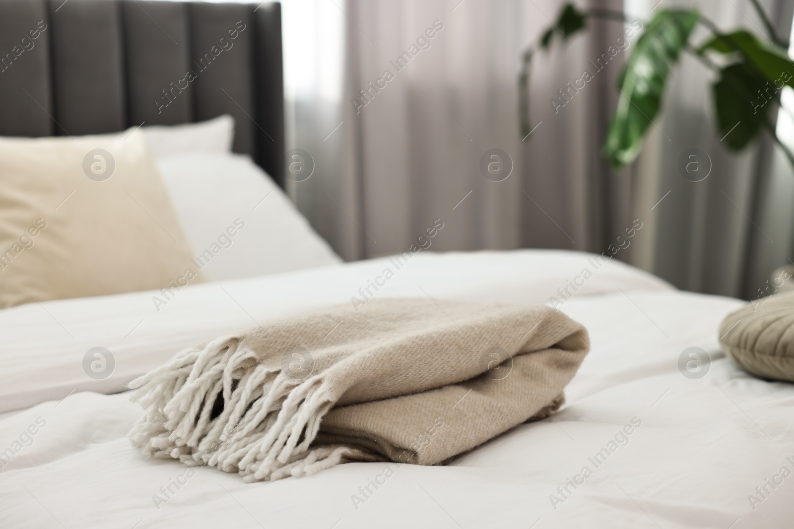 Photo of Soft beige plaid on bed in bedroom