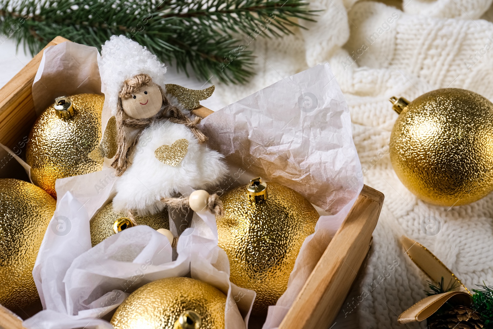 Photo of Beautiful golden Christmas baubles and toy in wooden crate, closeup