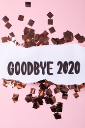 Flat lay composition with phrase Goodbye 2020 and confetti on pink background