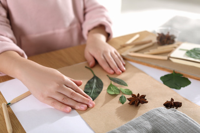 Photo of Little girl working with natural materials at table indoors, closeup. Creative hobby