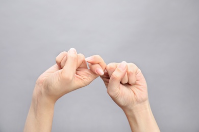 Photo of Woman showing word friend on grey background, closeup. Sign language