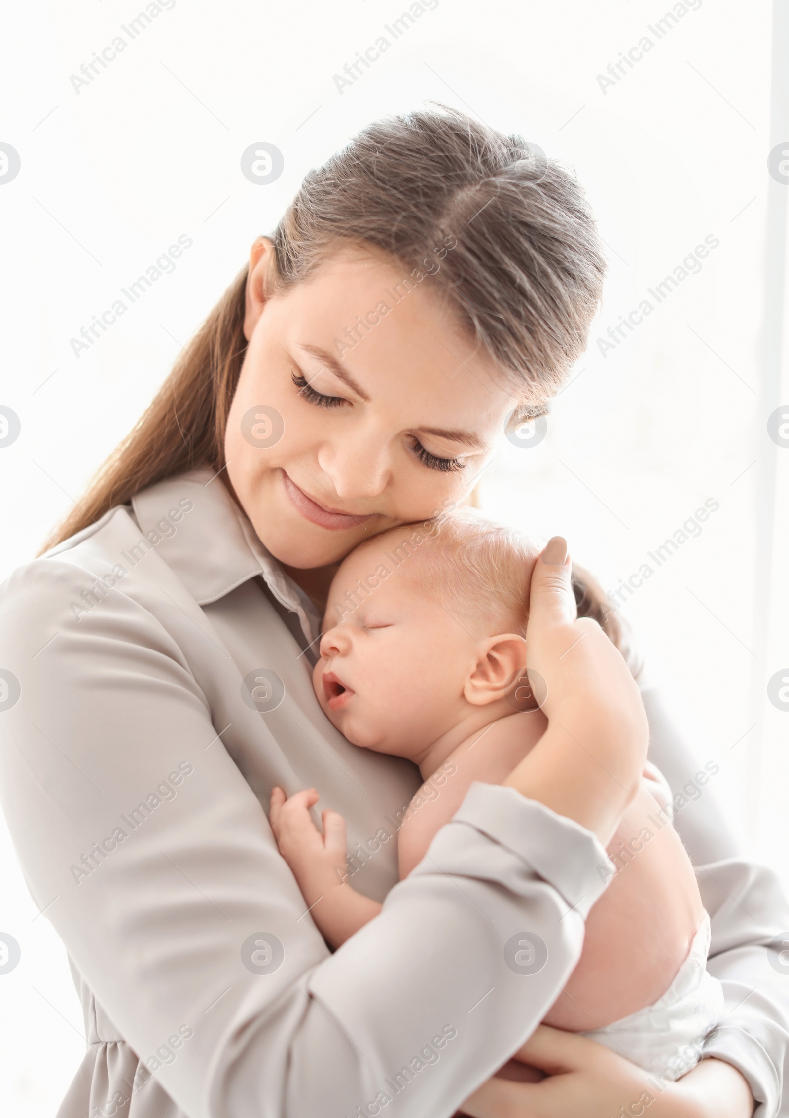 Photo of Young mother with her newborn baby on light background