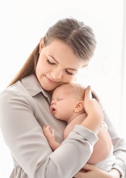 Young mother with her newborn baby on light background