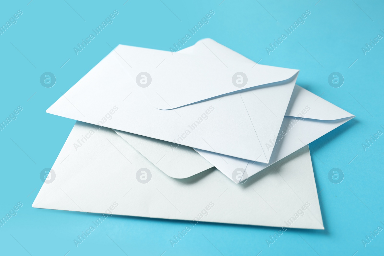 Photo of White paper envelopes on light blue background, closeup