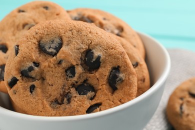 Photo of Bowl with many delicious chocolate chip cookies on table, closeup