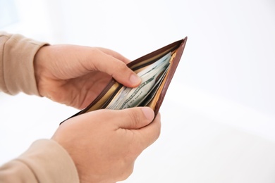 Man holding wallet with money indoors, closeup. Space for text