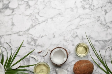 Jars of natural organic oil and coconuts on marble background, flat lay. Space for text