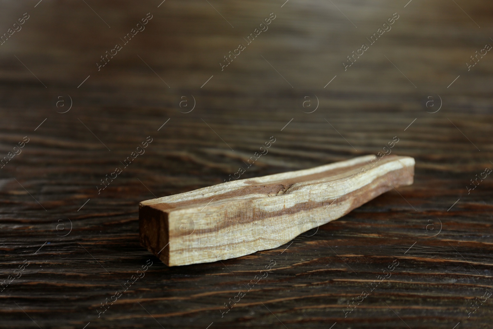 Photo of Palo santo stick on wooden table, closeup