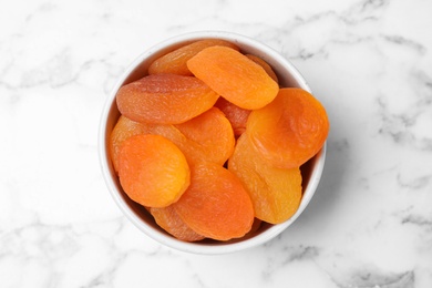 Photo of Bowl with apricots on marble background, top view. Dried fruit as healthy food