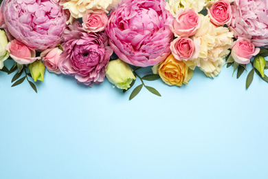 Photo of Flat lay composition with beautiful flowers and space for text on light blue background. Floral card design
