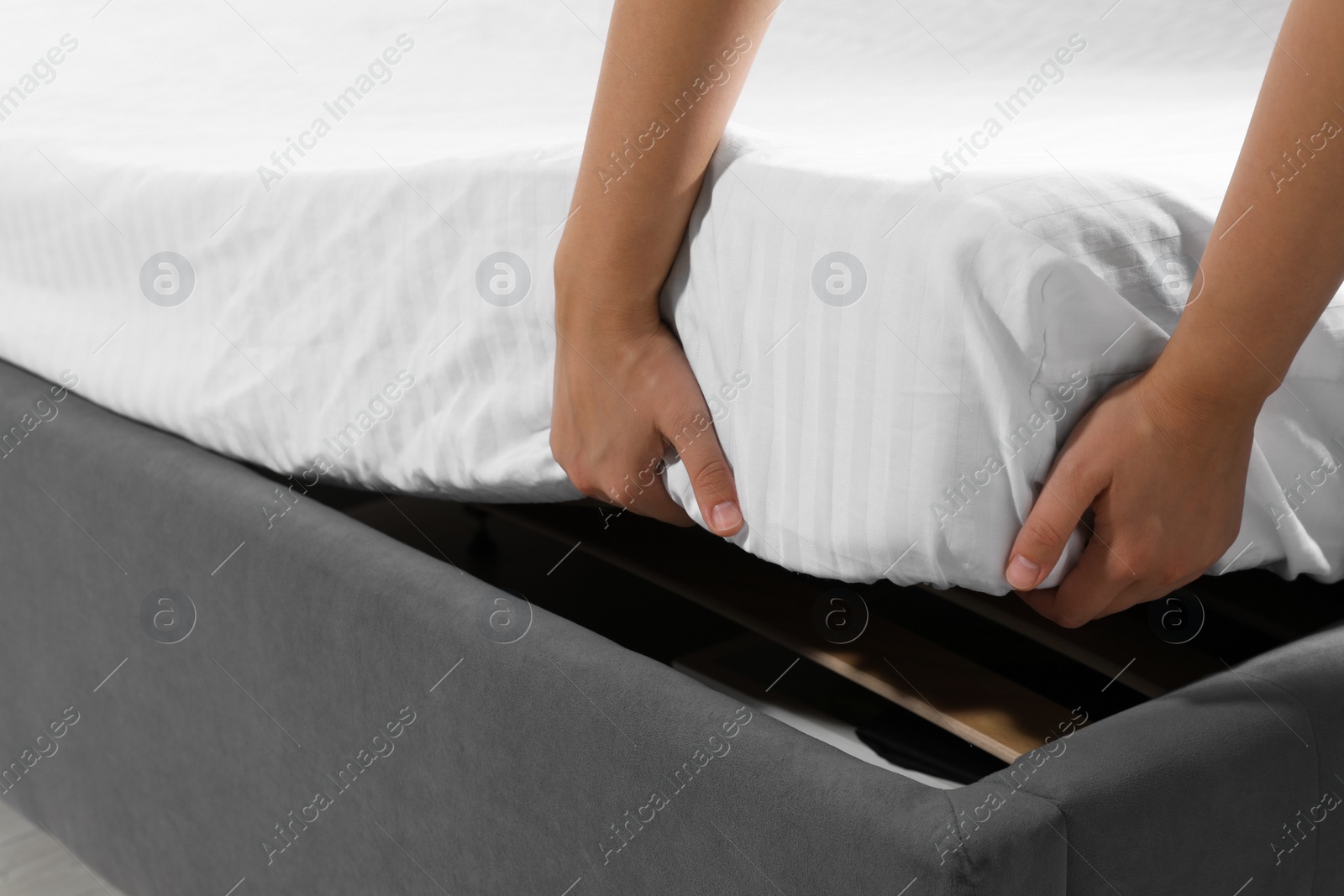 Photo of Woman covering mattress with protector, closeup view
