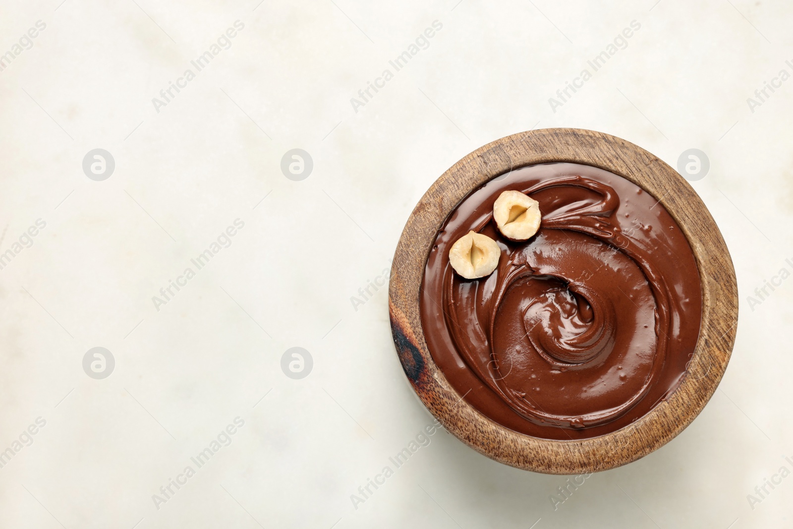 Photo of Bowl of tasty chocolate hazelnut spread on white background, top view. Space for text