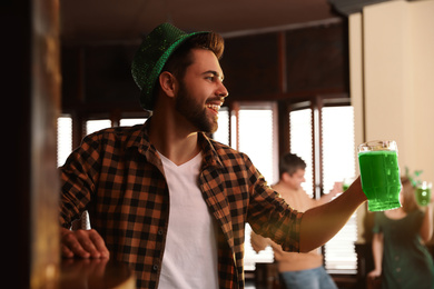 Photo of Young man with glass of green beer in pub. St. Patrick's Day celebration