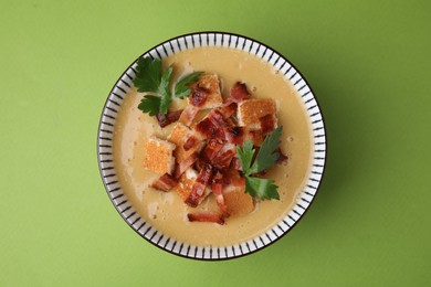 Photo of Delicious lentil soup with bacon and parsley in bowl on green table, top view