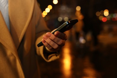 Photo of Woman with smartphone on night city street, closeup. Space for text