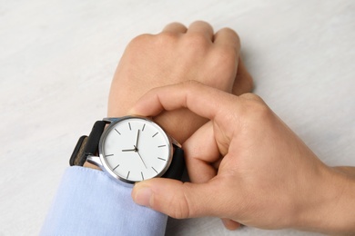 Photo of Businessman with stylish wrist watch at table, closeup