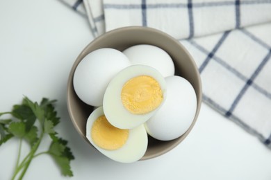 Photo of Bowl with hard boiled eggs on white table, flat lay