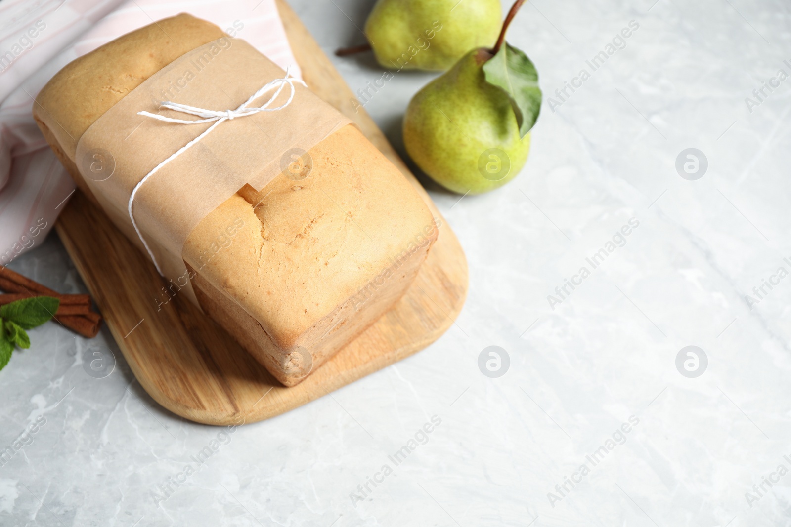 Photo of Tasty tied pear bread on light grey table, space for text. Homemade cake