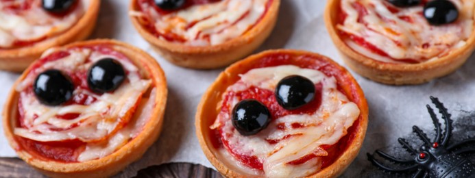 Image of Cute monster tartlets served on black wooden table, closeup. Banner design