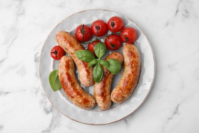 Photo of Plate with tasty homemade sausages, basil leaves and tomatoes on white marble table, top view