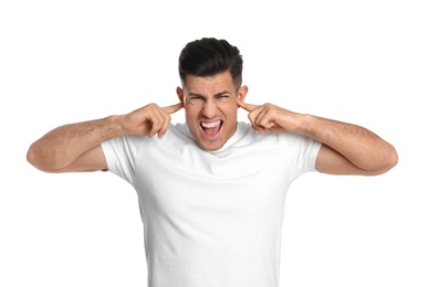 Emotional man covering ears with fingers on white background