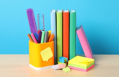 Photo of Composition with different school stationery on wooden table against light blue background. Back to school