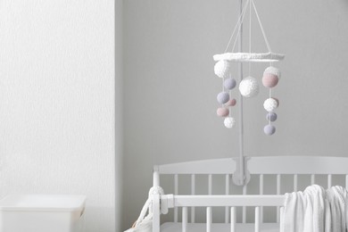 Photo of Modern crib with baby mobile in children's room. Interior design