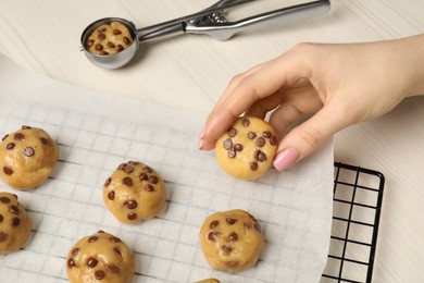 Photo of Woman making delicious chocolate chip cookies at white wooden table, closeup