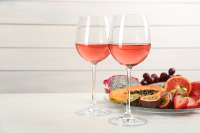 Delicious exotic fruits and wine on white wooden table. Space for text