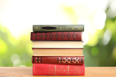 Image of Collection of different books on wooden table against blurred green background