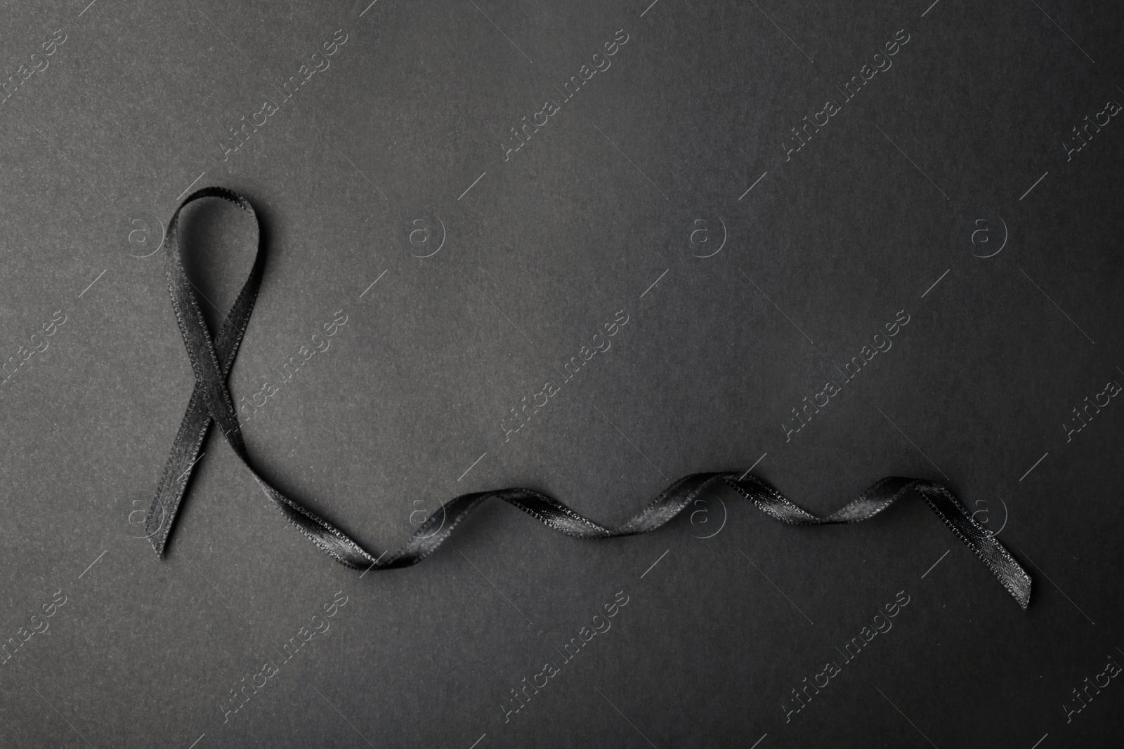 Photo of Black ribbon and space for text on dark background, top view. Funeral accessory