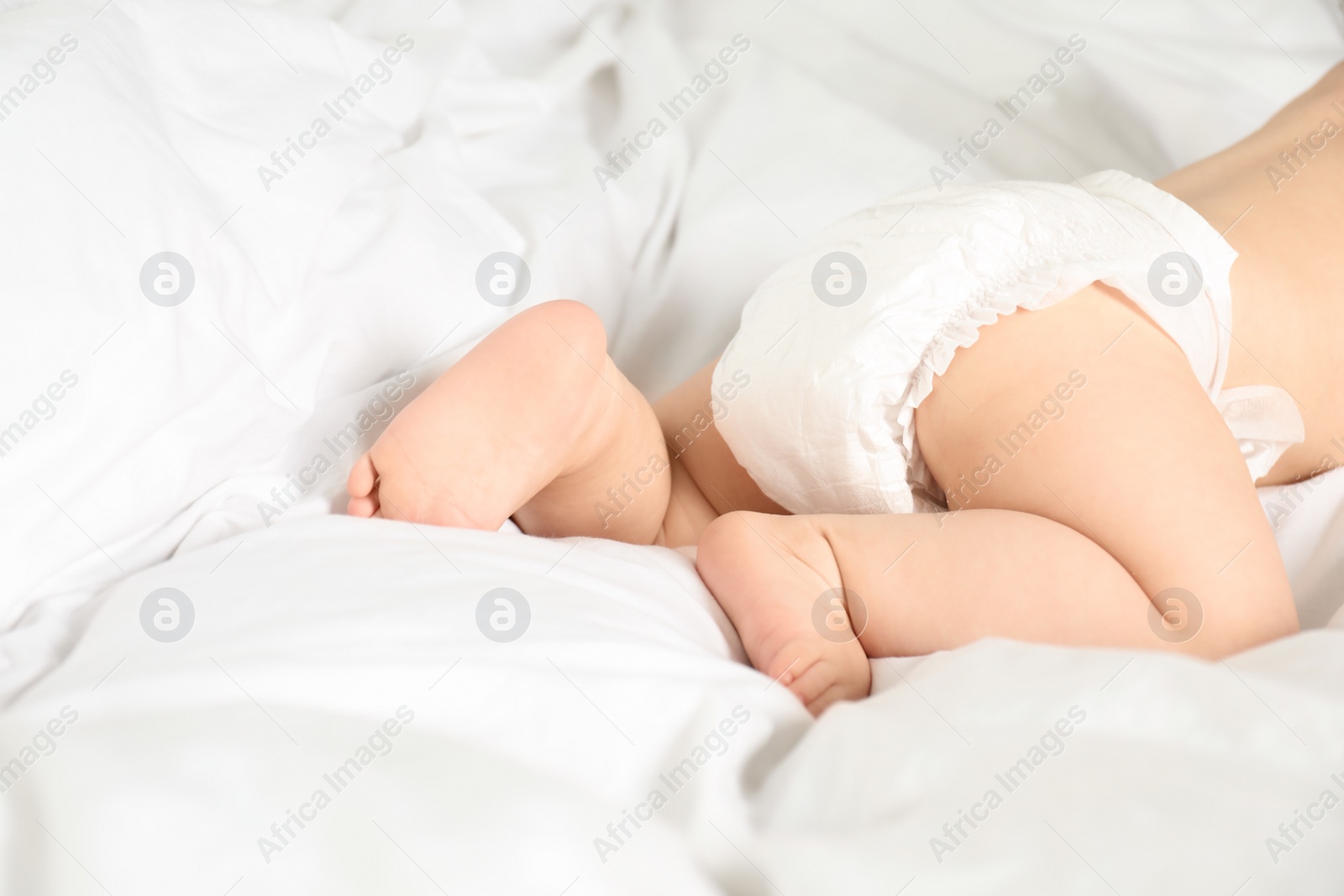 Photo of Cute little baby in diaper on bed, closeup