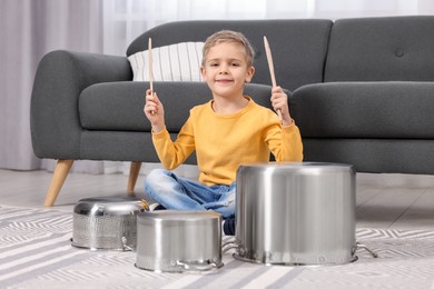 Photo of Little boy pretending to play drums on pots at home