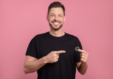 Photo of Happy man holding condom on pink background