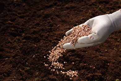 Man fertilizing soil, closeup. Space for text