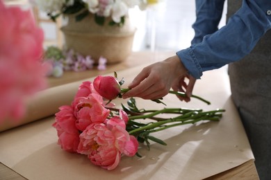 Florist making beautiful peony bouquet at table, closeup