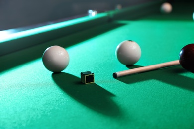 Billiard balls, cue and chalk on table indoors