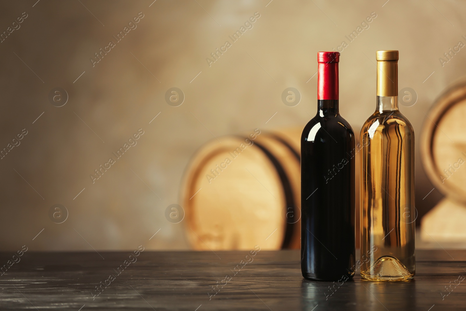 Photo of Bottles of delicious wine and blurred barrels on background