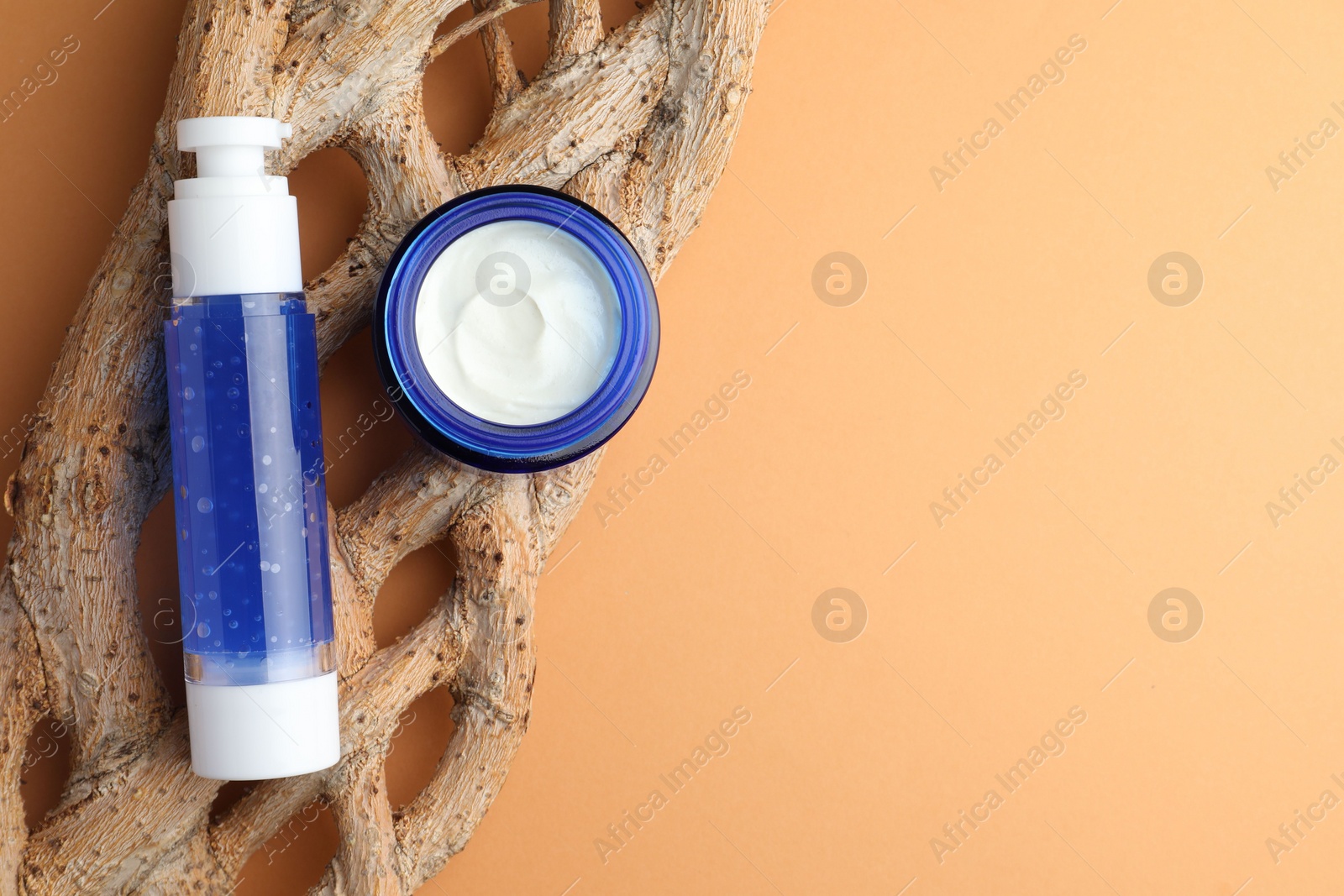 Photo of Bottle and jar of cosmetic products on orange background, top view. Space for text