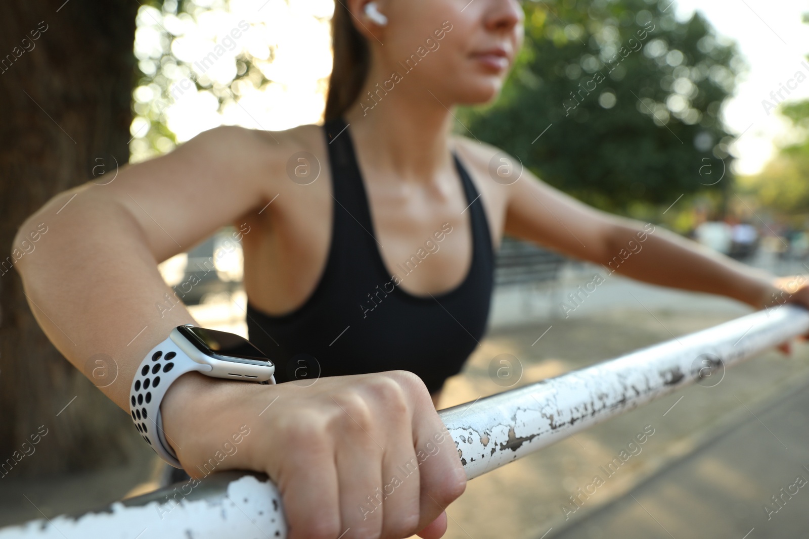 Photo of Woman wearing modern smart watch during training outdoors, closeup