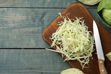 Photo of Chopped cabbage on blue wooden table, flat lay. Space for text