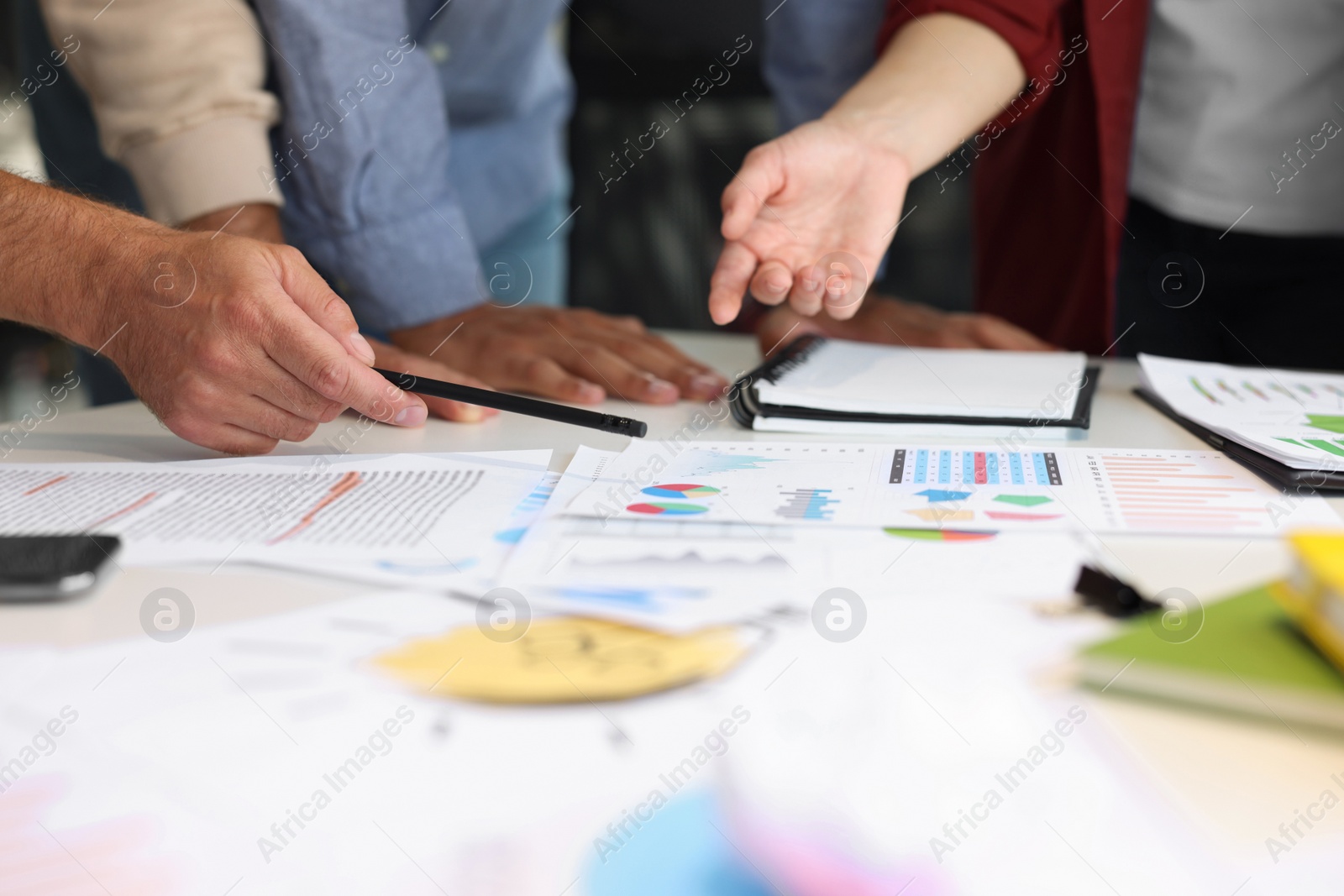 Photo of Team of employees working with charts at table, closeup. Startup project