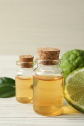 Glass bottles of bergamot essential oil on white wooden table