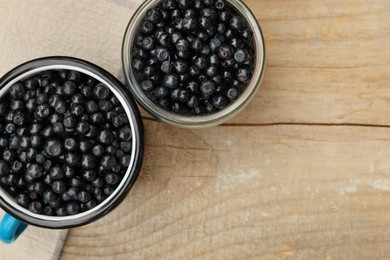 Photo of Jar and cup of delicious bilberries on wooden table, flat lay. Space for text