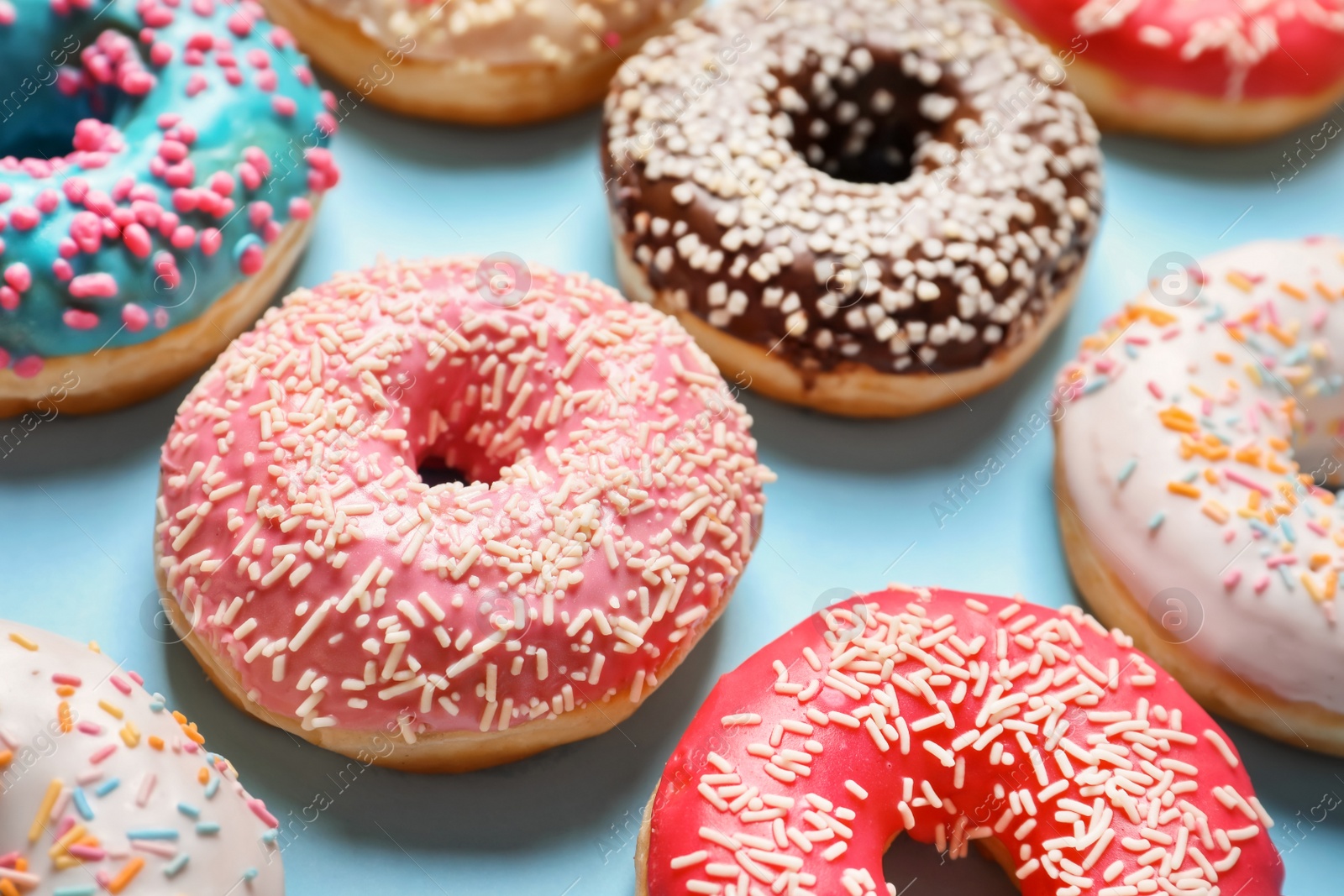 Photo of Delicious glazed doughnuts with sprinkles on color background