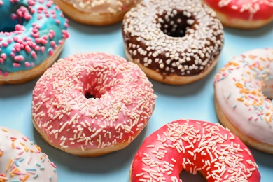 Delicious glazed doughnuts with sprinkles on color background