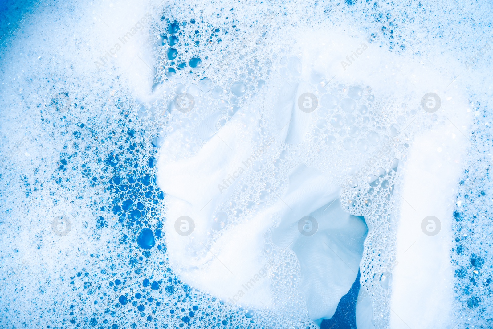 Photo of White garment in suds, closeup. Hand washing laundry