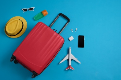 Photo of Flat lay composition with suitcase and travel accessories on light blue background. Summer vacation
